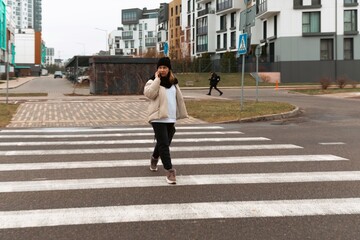 Person crossing a pedestrian walkway in a modern urban neighborhood during overcast weather