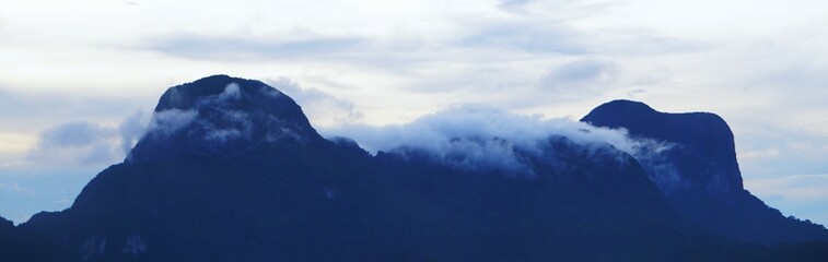 Wysokie góry i unoszące się nad nimi chmury. Panorama na tropikalne, wysokie góry na wyspie. Gęsta mgła rozpościerająca się nad górami. © Adam