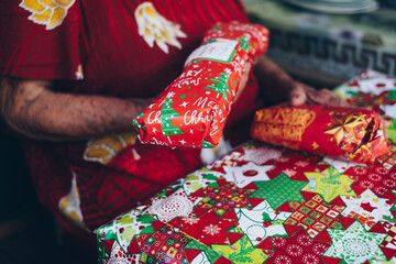 Closeup of old woman holding the received three Christmas gifts. Selective focus.
