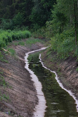 freshly dig drainage ditch with water in Latvia forest