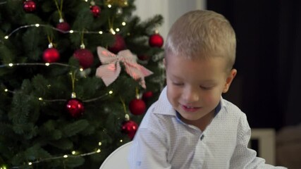 Happy child holding snow globe with figurine of Santa Claus. Smiling face of little boy near Christmas tree. Merry Christmas and Happy New year winter holidays.