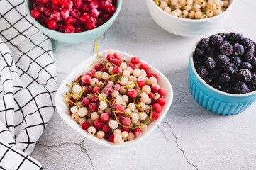 Frozen red and white currants in a bowl and other berries on the table