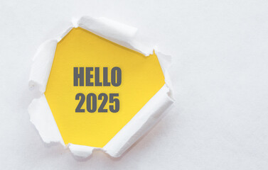 A yellow note with HELLO 2025 peeks through torn white paper, symbolizing a fresh start and...