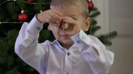 Happy child holding snow globe with figurine of Santa Claus. Smiling face of little boy near Christmas tree. Merry Christmas and Happy New year winter holidays.