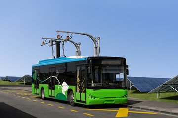 Electric bus at a stop is charged by pantograph. Solar panels in the background