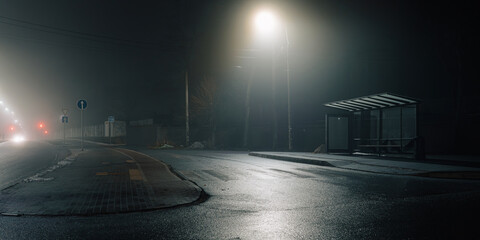 Urban night scene with a misty bus stop and glowing streetlights, emphasizing solitude and cinematic mood.