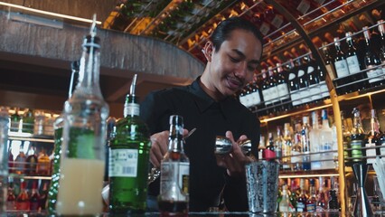 Asian bartender pouring mixed cocktail juice liqueur all ingredient into sliver shaker alcohol...