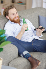 man drinking beer while watching tv on sofa