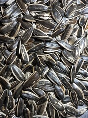sunflower seeds backgroundThe image shows striped sunflower seeds in a close-up view. They are scattered in a random pattern, forming a dense texture of alternating light and dark stripes on each seed