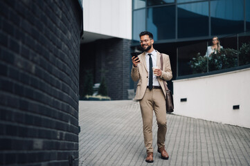 Smiling businessman walking and using smartphone app in city