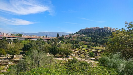 Athens, Greece - 30.3.2018: Aerial view of the broken columns and other relics at Ancient Agora with the Stoa of Attalos and Acropolis at the back under a sunny blue sky before the pandemic