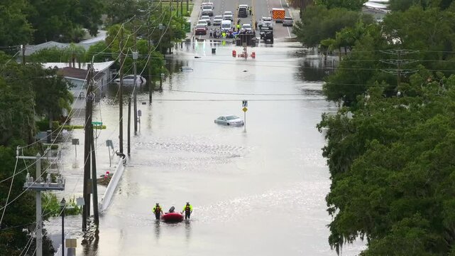 Rescue workers on flooded road. Emergency response in Florida residential area. Consequences of hurricane Debby natural disaster