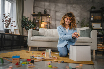 mother sit on the floor and put toys in basket after children playing