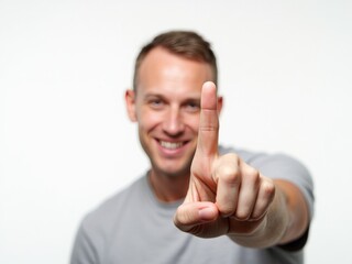 A Smiling Man in a Gray Shirt Raises One Finger, Signaling a Positive Point or Number in a Bright, Minimalist Space