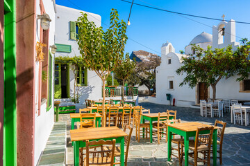 Obraz premium Square with white typical Greek church and tavern restaurant tables and chairs in Chora village, Folegandros island, Cyclades, Greece