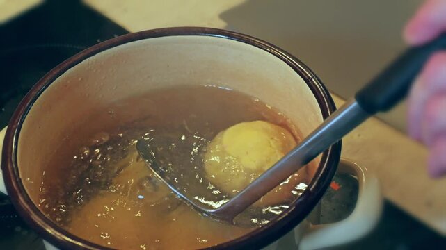Closeup of traditional Polish Meat-filled potato dumplings called Pyzy being cooked on a cooker