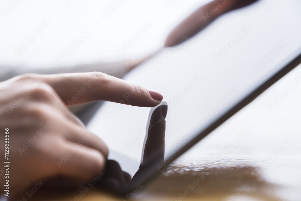 Poster closeup of a woman's finger making contact with a state-of-the-art tablet screen, device resting on 