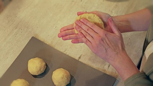 Closeup of housewife hands shaping traditional Polish Meat-filled potato dumplings called Pyzy with homemade dough In domestic kitchen setting