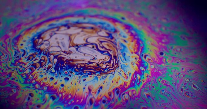 Vivid rainbow color. Swirls soap bubble. Defocused purple green liquid oil paint curve acrylic slick on dark black blurred light abstract background.