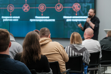 Obraz premium View of people attending a business seminar. Focus on speaker presenting information on digital screen.