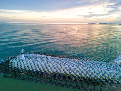 ADAPAZARI KARASU Aerial View of Coastal Breakwater with Lighthouse at Sunrise. A stunning aerial shot of a meticulously arranged breakwater, composed of numerous concrete blocks, extending into oceon