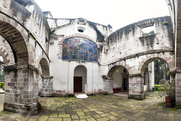 Fototapeta premium Historic courtyard with colorful stained glass in an old building on a cloudy day