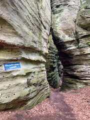 Paths between rocks in the forest in the Mullerthal region of Luxembourg, with the ground covered in dry leaves.
