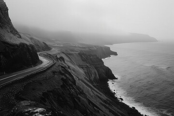 Scenic coastal road winding along dramatic cliffs and crashing waves under a cloudy sky in...