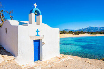 Small white Greek chapel on sea cliff at Alyko beach, Naxos island, Cyclades, Greece