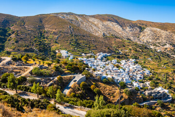White houses and buildings of Koronos mountains village located on high green hills, Naxos island,...