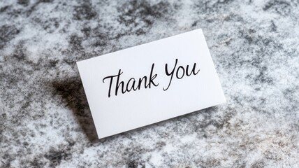 White card with "Thank You" written on textured background