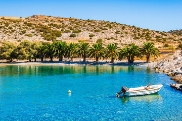 Boat on azure sea and palm trees on idyllic Panormos beach, Naxos island, Cyclades, Greece