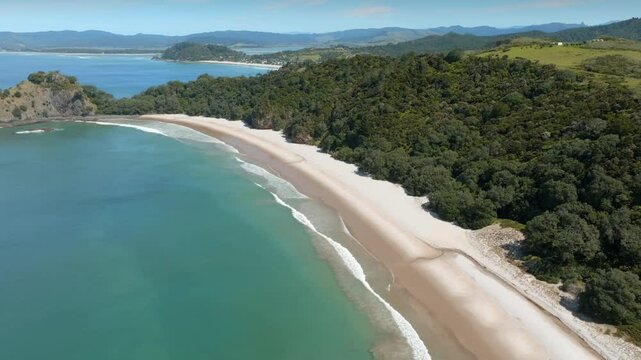 Stunning aerial view of a pristine beach nestled within lush New Zealand forest. Waves gently lap the shore, showcasing the beauty of nature. NEW CHUMS BEACH, WHANGAPOUA, COROMANDEL PENINSULA, NEW ZEA