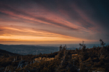 Obraz premium A beautiful sunset occurring over a hill with trees in the foreground