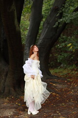 Young woman in white dress standing in the forest
