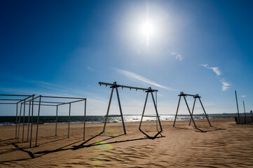 Plage vide avec des jeux d'enfants, sous un soleil d'hiver, en hors saison