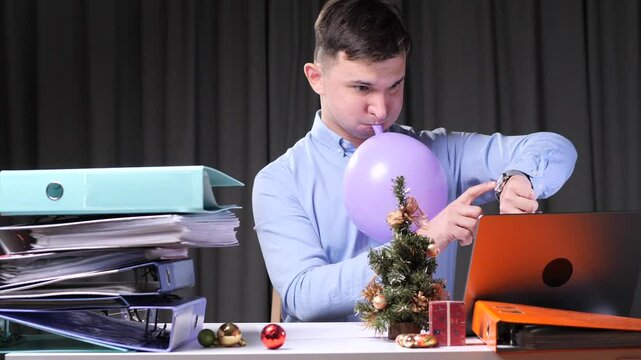 Office worker inflating balloon and checking time during christmas season