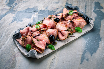 Traditional lunch meat with sliced cold cuts roast beef decorated with red cherries and capers as...
