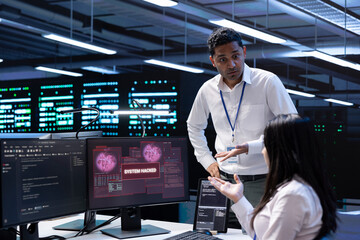 Programmers doing teamwork in server hub trying to protect hardware from hacker stealing...