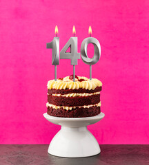 Birthday cake with number 140 candle - Red velvet on a fuchsia background.