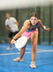 Sportive young woman and other members engaged in Padel Tennis in indoor court of tennis club