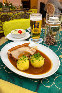 Traditional German beer Augustiner bear with Schweinebraten (roast pork) served with potato dumplings and cabbage salad in Munich, Germany