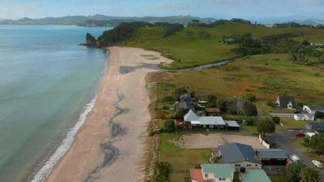 Coastal New Zealand town, homes nestled beside a beach, tranquil scene. SIMPSON BEACH, WHITIANGA, COROMANDEL PENINSULA, NEW ZEALAND