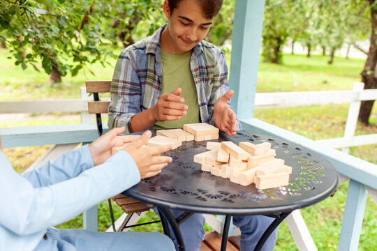 teenagers boy and girl playing in garden outdoors, kids building tower with wooden blocks and competing in educational board game, close up