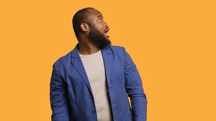 Obraz premium Smiling man having friendly conversation with friend sitting off camera, isolated over studio background. BIPOC person having fun catching up with mate, having lively discussion, camera A
