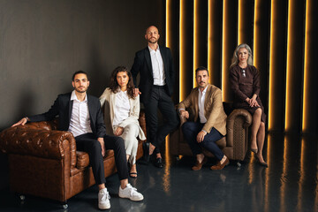 A group of five European executives stands in a stylish office environment. They are dressed in...