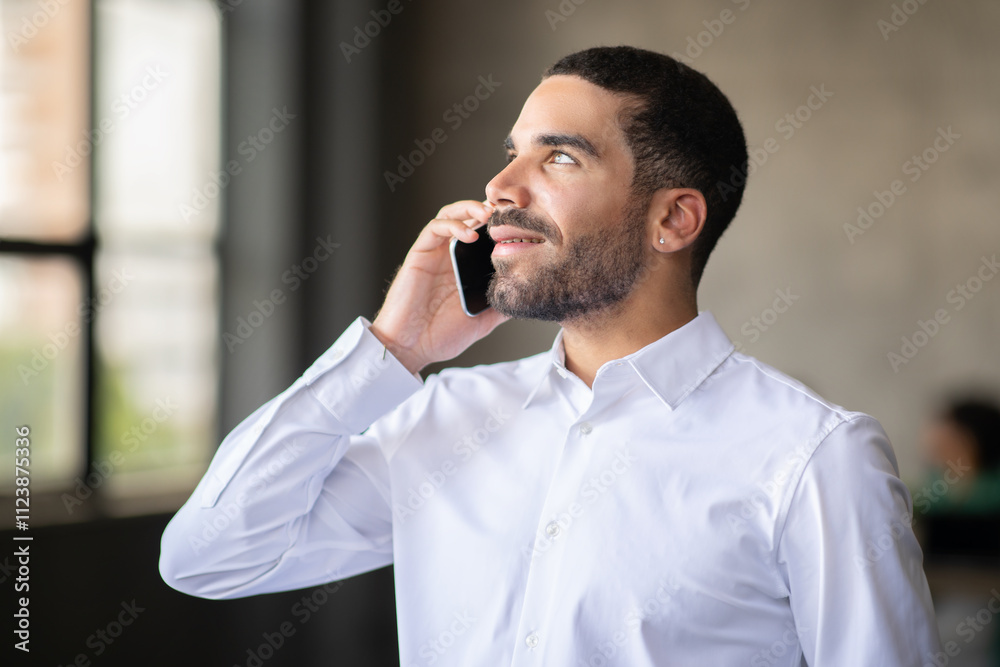 Aufkleber a businessman in a white shirt talks on the phone while standing in a contemporary office. natural l