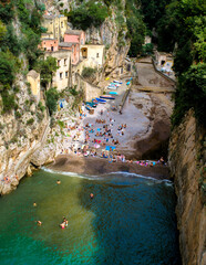 Basking in the warmth of the Italian sun, visitors relax on the pebble beach of a hidden cove along...
