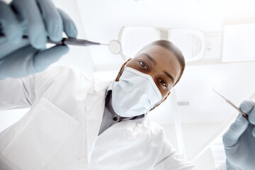 Black male dentist doctor with sterile dental tools in hands, low angle view. Portrait of african...