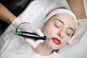 Naklejka premium A young woman relaxes as a skilled makeup artist applies a long-lasting lip color treatment. This pampering beauty procedure takes place in a comfortable salon setting.